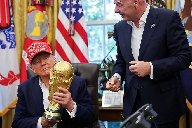 진나해 8월 22일 미국 워싱턴 백악관 오벌 오피스에서 도널드 트럼프 미국 대통령이 2026년 FIFA 월드컵 개최지 발표를 하며 FIFA 월드컵 트로피를 들고 있다. 그의 옆에는 잔니 인판티노 FIFA 회장이 서 있다. 로이터=연합뉴스