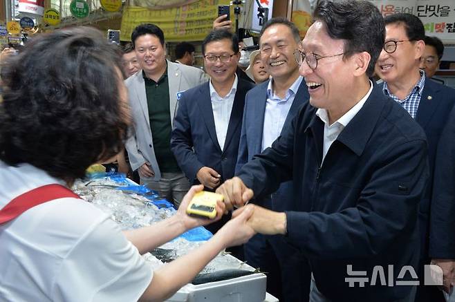 [목포=뉴시스]박상수 기자 = 8일 오후 전남광주 목포시 동부시장을 찾은 김민석 전 국무총리가 생선가게 상인과 손을 잡으며 웃고 있다. 2026,07.08. parkss@newsis.com
