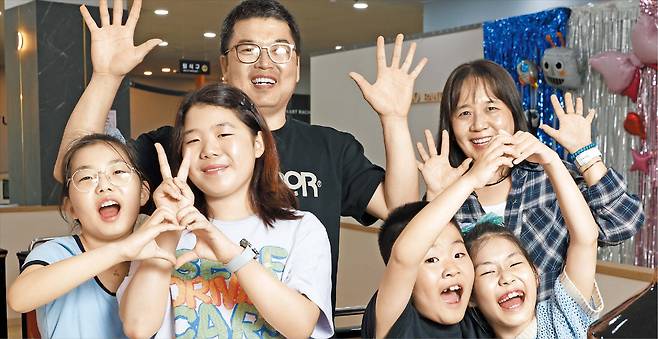 정경식 기자김보연·김명훈 부부와 네 아이가 웃으면서 손으로 하트모양을 만들거나 손을 흔들고 있는 모습. 왼쪽부터 효정·다정·서정·채정이다. 부부는 “육아로 힘든 것보다 아이들이 주는 행복이 훨씬 큰 만큼, 아이를 낳기 전에 걱정부터 하지 않았으면 좋겠다”고 했다.