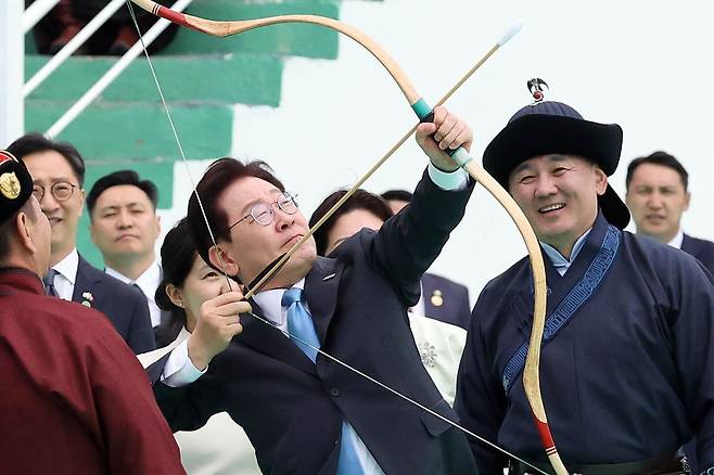 몽골을 국빈방문 중인 이재명 대통령이 11일(현지시간) 울란바타르 나담축제장에서 전통 활을 쏘고 있다. 오른쪽은 오흐나 후렐수흐 몽골 대통령. 연합뉴스