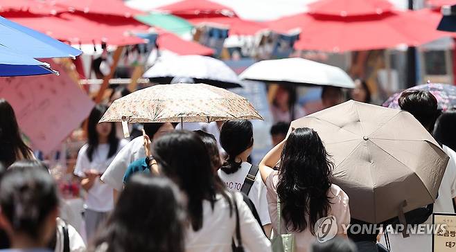 폭염 속 대구 동성로 (대구=연합뉴스) 윤관식 기자 = 대구에 폭염 경보가 발효된 11일 대구 중구 동성로에 상인들이 파라솔을 설치한 가운데 시민들이 양산을 쓰고 이동하고 있다. 2026.7.11 psik@yna.co.kr