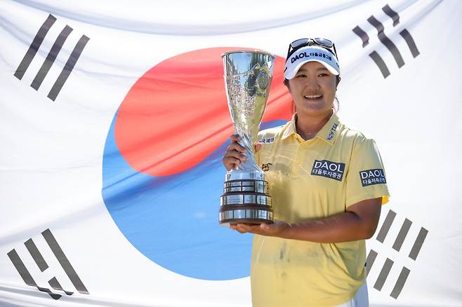 유해란이 12일(한국시간) 에비앙 챔피언십에서 메이저대회 2연승을 달성하며 시즌 2승, 통산 5승을 신고한 뒤 챔피언 트로피를 들고 태극기 앞에서  환하게 웃고 있다. 에비앙레뱅  |   AP뉴시스