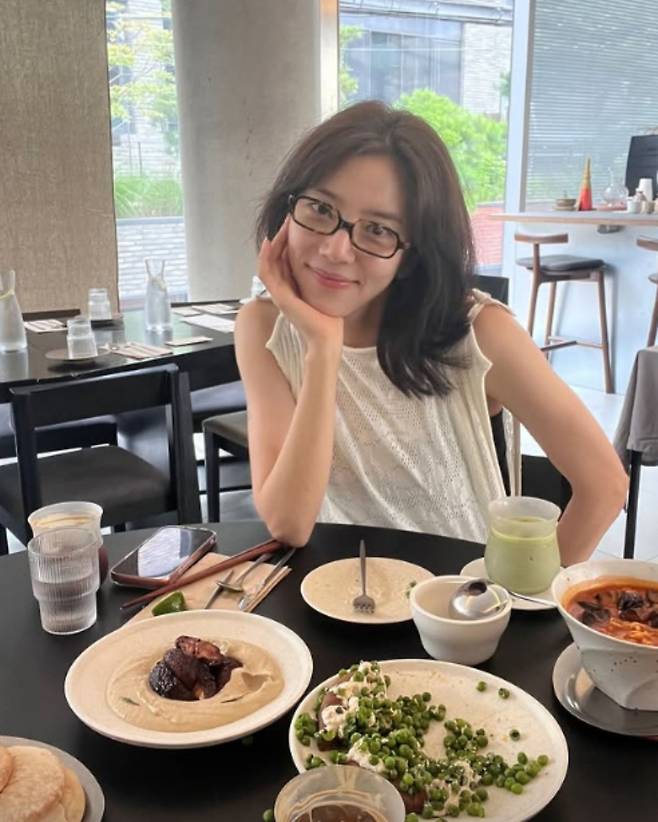 Singer and actress Son Dam-bi has drawn attention by showcasing a stylish layered look featuring a uniquely designed knit top reminiscent of an apron. Son Dam-bi shared an update on her recent visit to a restaurant via her personal social media channel, revealing a fashion style that is both comfortable and full of personality.In the photos, Son Dam-bi paired a white sleeveless knit top with wide-leg denim pants to create a sophisticated look. In particular, the knit fabric, which draped long in the front and back, created a unique silhouette that looked as if she were wearing an apron, capturing everyones attention.She accessorized with a black shoulder bag and horn-rimmed glasses, and added a pink jacket to complete the fresh color palette. Son Dam-bi shared a glimpse of her relaxed daily life, noting that she had spent a pleasant time with a friend.Meanwhile, Son Dam-bi married former speed skater Lee Kyu-hyuk in 2022 and is currently the mother of a daughter. She actively shares her daily life with her family and communicates with fans through her personal social media accounts and YouTube channel.