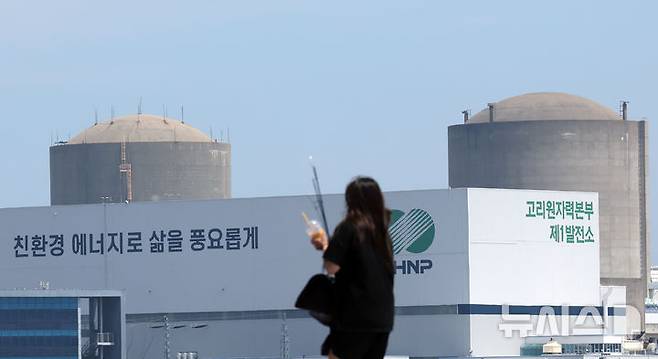 [부산=뉴시스] 하경민 기자 = 부산 기장군이 0.7GW급 국내 첫 소형모듈원자로(SMR) 1기의 건설 후보지로 선정된 가운데 18일 기장군의 한 방파제를 지나는 시민 뒤로 고리원전 1~2호기가 보이고 있다. 2026.06.18. yulnetphoto@newsis.com