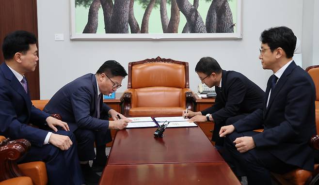 한병도 더불어민주당 대표 직무대행 겸 원내대표와 정점식 국민의힘 원내대표가 21일 서울 여의도 국회 운영위원장실에서 제9회 전국동시지방선거 투표용지 부족 사태 등 선거관리 부실 사태의 진상규명을 위한 특별검사의 임명 등에 관한 법률안 합의문에 서명하고 있다. 왼쪽부터 김승수 국민의힘 원내수석부대표, 정 원내대표, 한 직무대행, 천준호 더불어민주당 원내운영수석부대표. 공동취재사진
