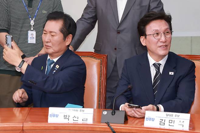 더불어민주당 정청래 당 대표 후보가 20일 국회에서 열린 민주당 공명선거 실천 서약식에 참석해 최고위원 후보 기념 촬영을 취재하는 취재진을 촬영하고 있다. 오른쪽은 김민석 당 대표 후보. 연합뉴스