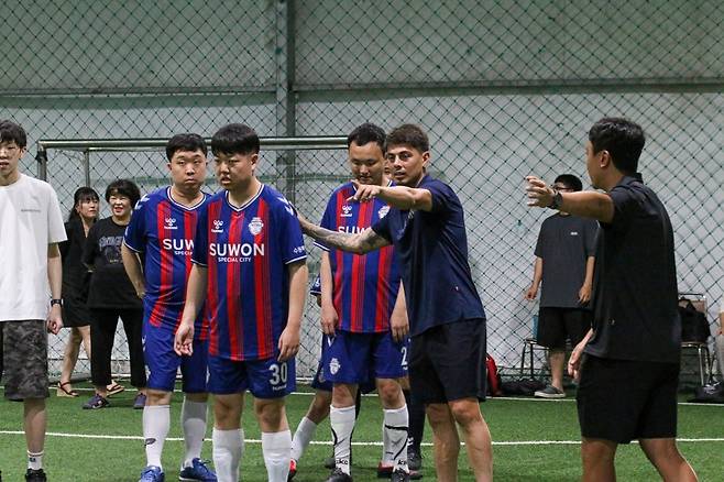 수원FC 선수단이 22일 수원시티FC 풋살장에서 수원시장애인축구협회 소속 성인 회원 30여 명을 대상으로 축구 클리닉을 진행하고 있다.
