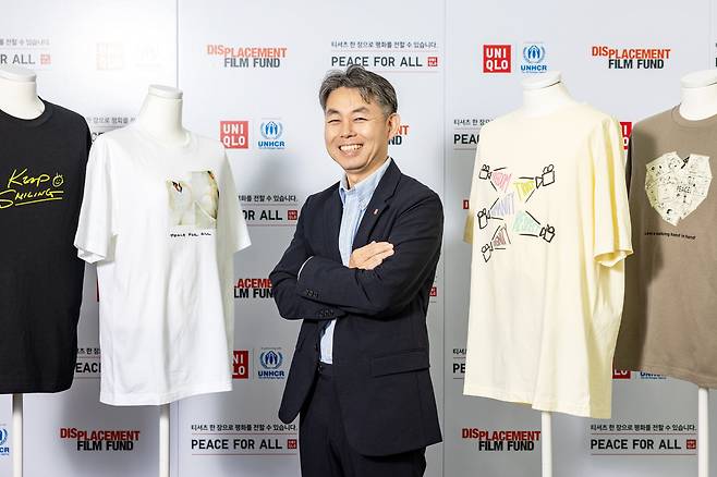 야나이 고지 패스트리테일링그룹 수석 집행 임원이 유니클로의 자선 기부 티셔츠 ‘피스 포 올’ 사이에 섰다. 티셔츠 판매 수익금은 폭력·차별·무력분쟁·빈곤으로 고통받는 이들을 돕는 국제기구에 기부된다./장은주 영상미디어 객원기자