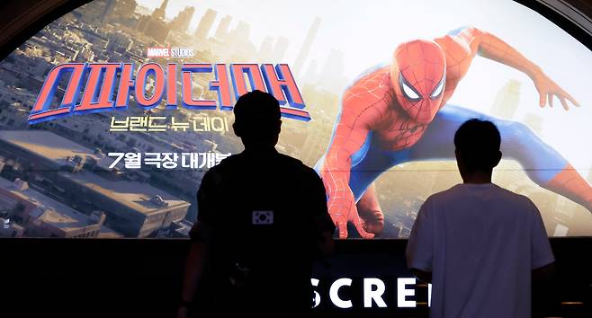 톰 홀랜드가 주연한 영화 '스파이더맨: 브랜드 뉴 데이' 대형 포스터를 극장 관람객들이 살펴보고 있다./뉴시스