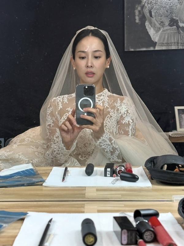 Actress Cho Yeo-jeong shared behind-the-scenes photos on her social media of herself dressed in a wedding dress and Hanbok with Kim Jae-chul during the filming of the Coupang Play series *Adultery Is Not the Issue Right Now*. Although they appear in the series as a former couple in the midst of a divorce lawsuit, the actual filming set displayed a warm and friendly atmosphere, revealing a contrasting charm.Cho Yeo-jeong perfectly recreated the look of a bride, posing affectionately with Kim Jae-chul while wearing a wedding dress and a traditional Korean hanbok for the Pyebaek ceremony. Scenes reminiscent of a real wedding, such as a kiss on the cheek directed at Kim Jae-chul, particularly caught the eye.In the series, Cho Yeo-jeong plays the role of Su-jeong, a dermatologist, while Kim Jae-chul plays the role of her ex-husband, Bo-seong, portraying a conflicting relationship engaged in a messy divorce lawsuit. Cho Yeo-jeong mentioned that they live as a loving couple off-camera, conveying the atmosphere on set that contrasted sharply with their on-screen relationship.Adultery Is Not the Issue is a black comedy drama about a popular influencer couple and a doctor couple who become entangled in a huge secret. Starring Kim Hye-soo, Cho Yeo-jeong, Kim Ji-hoon, and Kim Jae-chul, it was released on Coupang Play on July 31.