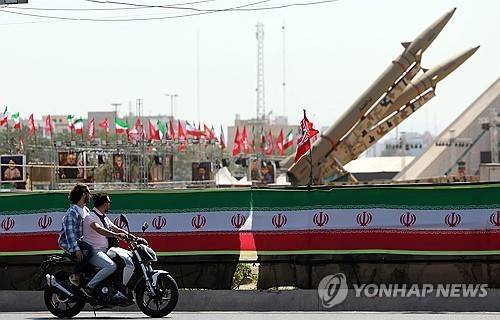 이란 테헤란 아자디 광장에서 오토바이 운전자들이 이란의 탄도미사일 졸파가르 옆을 지나고 있다. [EPA 연합뉴스. 재판매 및 DB 금지]