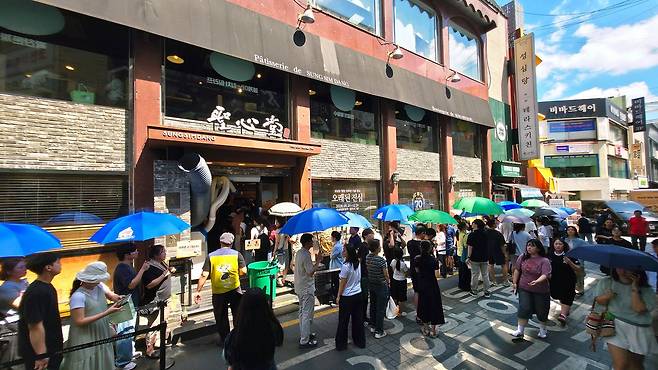 대전 대표 빵집 '성심당'앞에 고객들이 양산을 쓴 채 줄을 서 기다리고 있다. 성심당측은 고객에게 생수와 양산 등을 제공하고 있다.. 김성태 객원기자