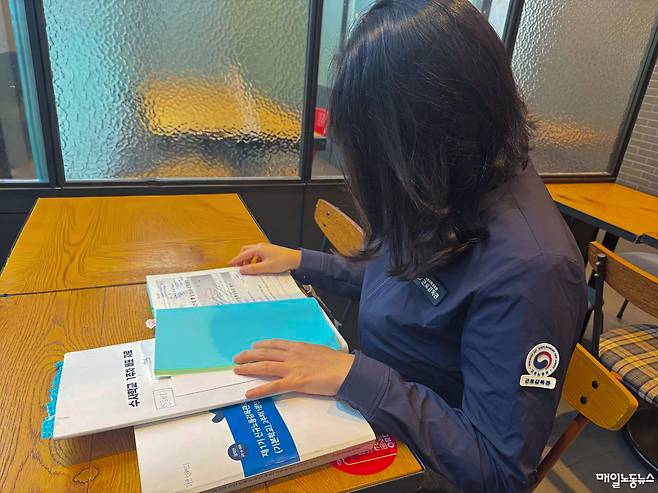 ▲ 신혜리 감독관이 연수시절 공부한 교재를 보고 있다. 신 감독관의 요청으로 얼굴은 공개하지 않는다. <김학태 기자>