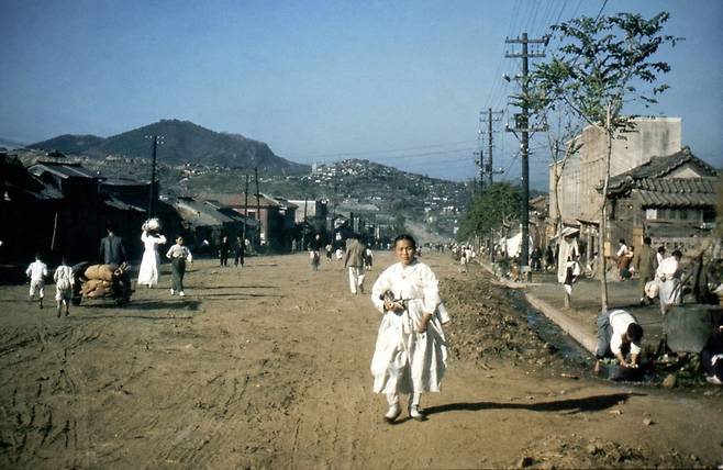 1945년 광복 직후 서울 신촌의 진창길. 비포장도로 양옆으로 낮은 집들이 늘어서 있고 주민들이 오가고 있다. 국가기록원 소장 원본을 생성형 인공지능(AI)으로 복원해 화질을 개선했다. 국가기록원 제공