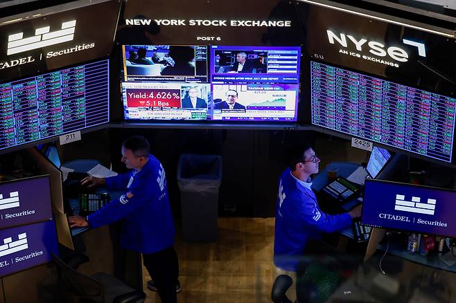 트레이더들이 지난 7일 뉴욕증권거래소(NYSE)에서 거래 현황을 알리는 화면을 들여다보고 있다. [로이터]