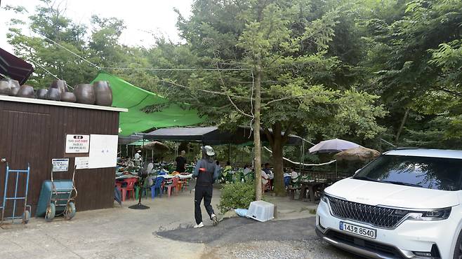 A staff member at a restaurant beside a valley in Namhansanseong directs diners to tables and the section of the stream directly in front of the restaurant. WOO JI-WON
