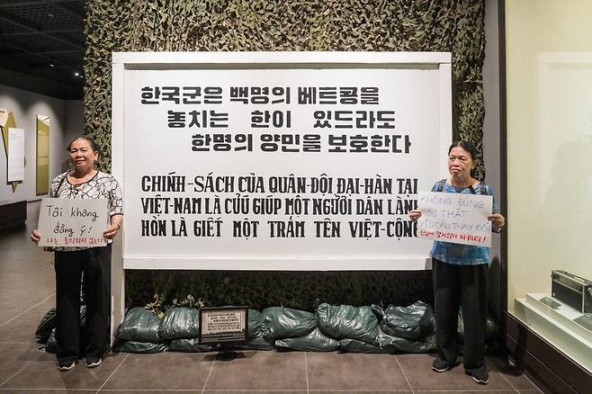 베트남전쟁 시기 한국군의 민간인 학살 생존 피해자 2명이 지난해 6월 22일 서울 용산구 전쟁기념관 해외파병실을 찾아 초대 주월한국군사령관 채명신 장군의 훈령 입간판 좌우에 서 있다. '응우옌티탄'이라는 같은 이름을 가진 동명이인인 이들은 "나는 동의하지 않는다" "진실에 맞지 않다, 바꿔라!"라고 쓴 종이를 들고 항의했다. '탄탄이' 제공
