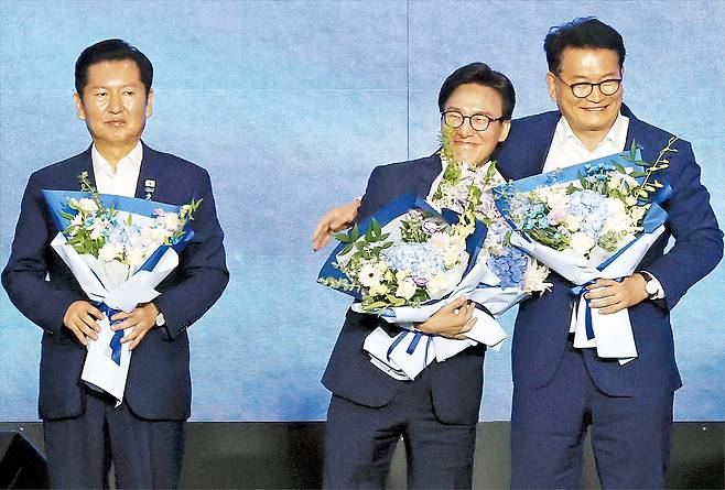 더불어민주당 김민석(가운데) 신임 당대표가 17일 대전에서 열린 전당대회에서 당선 확정 후 무대에 올라 경쟁자였던 송영길 후보와 포옹하고 있다. 그 옆에는 낙선한 정청래(왼쪽) 후보가 꽃다발을 들고 서 있다. /신현종 기자