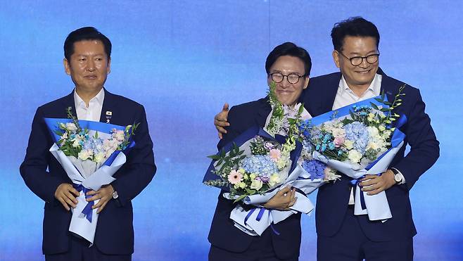 더불어민주당 당 대표에 출마한 김민석 전 총리가 17일 대전 컨벤션센터에서 열린 제3회 더불어민주당 정기 전국당원대회에서 당 대표 당선을 확정한 뒤 본선에서 경쟁을 벌였던 정청래 전 대표, 송영길 의원과 꽃다발을 들고 있다.[연합]