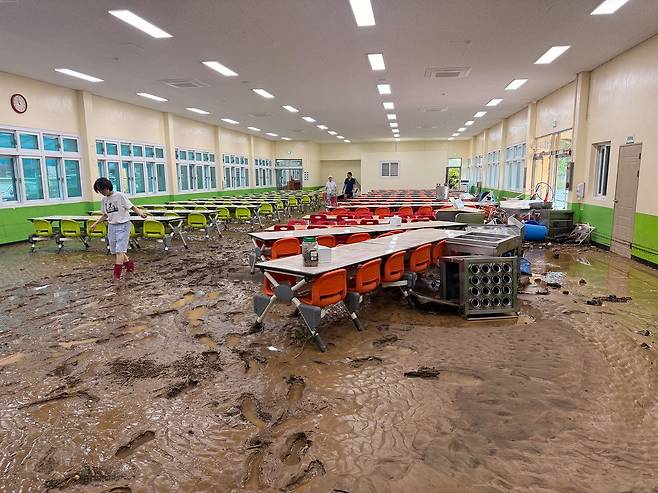 18일 오전 기록적인 폭우로 큰 피해가 발생한 경남 거제시 한 학교에서 교직원들이 침수된 책상과 의자 등에 쌓인 토사를 치우고 있다. [뉴시스]