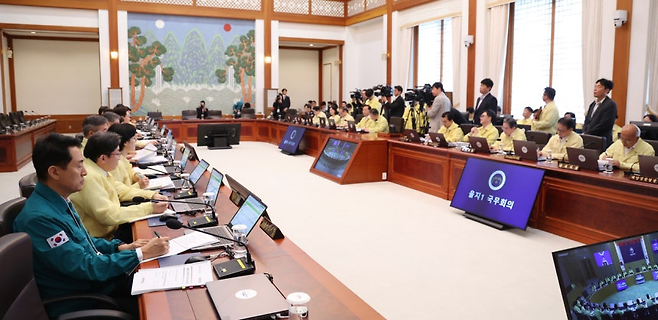 오세훈(왼쪽) 서울시장이 18일 청와대에서 열린 을지국무회의에서 이재명 대통령 발언을 듣고 있다. 참석자 중 오 시장만 청록색 민방위복을 입고 있다. [연합]