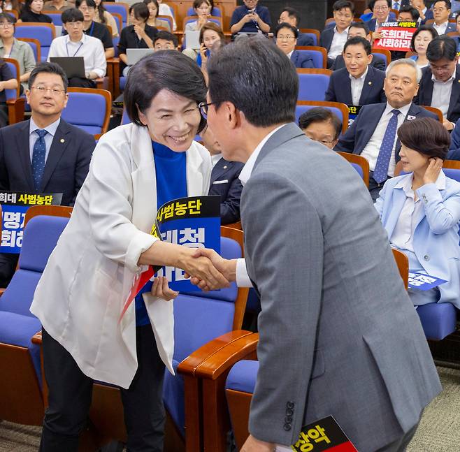 더불어민주당 최민희 최고위원(왼쪽)이 20일 국회에서 전당대회 뒤 처음으로 열린 의원 총회에서 김민석 대표와 악수하고 있다. /연합뉴스