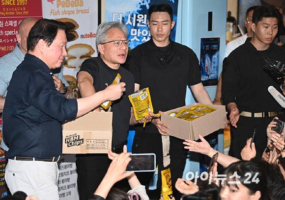 젠슨 황 엔비디아 최고경영자(CEO)가 지난 6월 5일 서울 마포구 서교동의 한 고깃집에서 최태원 SK회장 등과 함께 한 삼겹살 회동에서 시민들에게 HBM 칩을 나눠주고 있다. [사진=곽영래 기자]