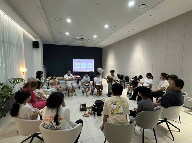 포천문화관광재단 다문화가족 문화예술교육 프로그램 ‘우리 집은 두 개의 언어를 씁니다’에 참여한 가족들이 원을 둘러앉아 기타와 타악기 등을 활용한 음악 활동에 참여하고 있다. 포천문화관광재단 제공