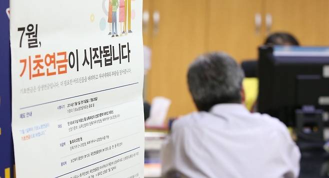 2014년 7월 25일 기초연금 첫 지급일을 하루 앞둔 24일 오후 서울 국민연금 종로중구지사 기초연금 접수 창구를 찾은 한 수급 대상자가 담당자와 상담하고 있다. [연합]