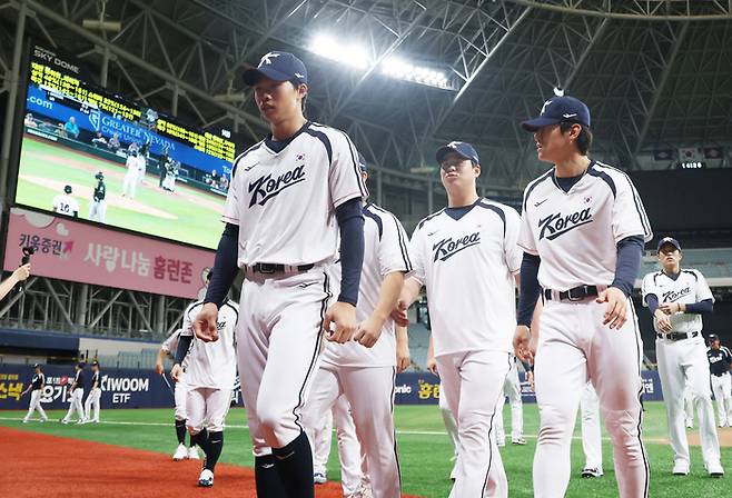 2026 아시안게임에 출전하는 한국 야구 대표팀 김도영 등 선수들이 15일 고척스카이돔에서 열린 공식 훈련에서 몸을 푼 뒤 더그아웃으로 들어가고 있다. 선수들 뒤로는 첫 상대인 대만 선수의 경기 영상이 재생되고 있다. 사진 | 고척=연합뉴스