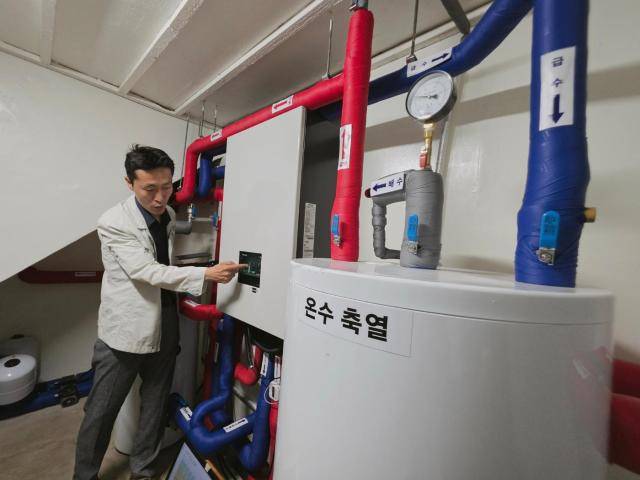 14일 제주 제주시 도남동의 한 단독주택 지하실에서 삼성전자 관계자가 히트펌프 시스템의 작동 상태를 설명하고 있다. 오른쪽은 200ℓ 규모 온수탱크.[사진=기후에너지환경부 공동취재단]