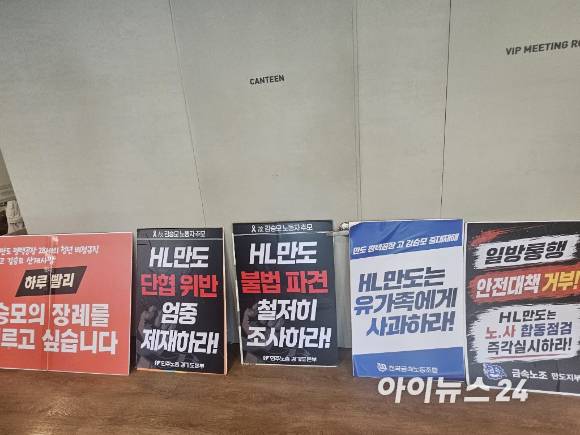 21일 HL만도 판교 사옥 기자회견장 입구에 ‘HL만도 불법 파견 철저히 조사하라’, ‘HL만도는 유가족에게 사과하라’ 등 고 김승모 군 유족과 노조 측이 가져온 항의 피켓들이 놓여 있다. [사진=설재윤 기자]