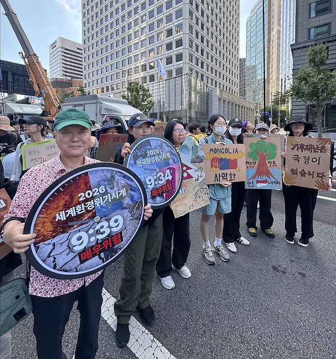 19일 서울 중구 태평로 일대에서 열린 9·19기후정의행진에서 최열(맨 왼쪽) 환경재단 이사장과 재단 관계자들이 '환경위기시계'가 그려진 손팻말을 들고 서 있다. 올해 세계환경위기시계는 오후 9시 39분을, 한국환경위기시계는 오후 9시 34분을 가리켰다. 환경재단 제공