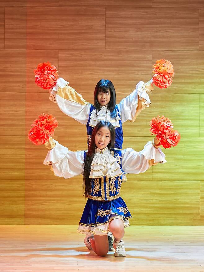 김서연(위) 학생기자와 채서현 학생모델이 퀸즈 단복을 입고 응원 도구인 팜(Pom)을 들어 포즈를 취했다.