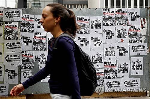 벽보 사이를 무심히 지나가는 유권자 [로이터=연합뉴스]
