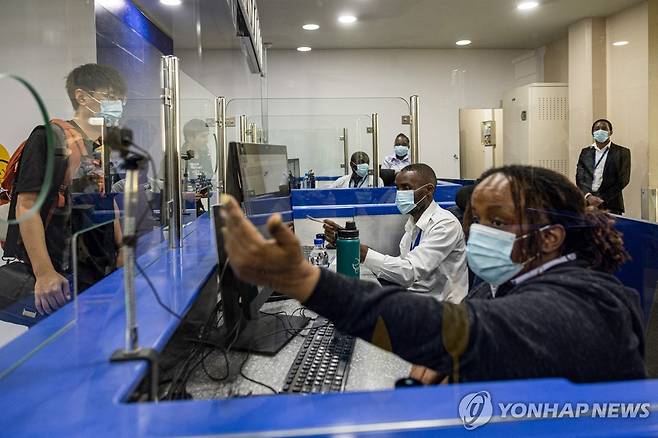 7일(현지시간) 케냐 나이로비 국제공항에서 세관 공무원이 마스크를 착용한 채 입국자의 여권과 신원을 확인하고 있다. [AFP=연합뉴스. 재판매 및 DB 금지]