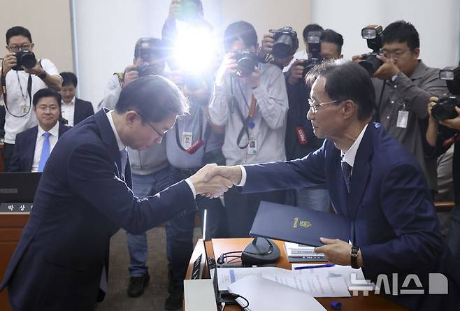 [서울=뉴시스] 김근수 기자 = 이억원 금융위원장이 8일 서울 여의도 국회에서 열린 정무위원회 국정감사에서 유동수 정무위원장에게 증인선서문을  전달하고 있다. 2026.10.08. ks@newsis.com