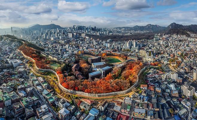 내년 유네스코(UNESCO) 세계문화유산 등재 심사를 받을 ‘한양의 수도 성곽’ 중 핵심인 한양도성의 낙산 구간. 조선시대 도성 안팎의 생활상을 현대에도 함축적으로 보여준다. 지난해 늦가을 정부 의뢰를 받은 서헌강 작가가 드론을 띄워 찍은 수천장의 사진 중 18장을 이어붙여 파노라마 기법으로 완성한 작품이다. /서헌강 작가