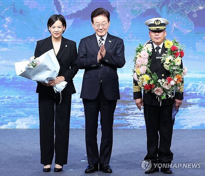 이재명 대통령, 북극항로 시범 운항 귀항 격려 (부산=연합뉴스) 한상균 기자 = 이재명 대통령이 13일 부산에서 열린 북극항로 시범 운항 환영식에서 팬스타 아크로호 서명원 선장에게 꽃목걸이를 전달한 후 가족과 기념 촬영을 하고 있다. 2026.10.13 [청와대 통신사진기자단] xyz@yna.co.kr