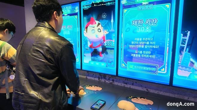 기자가 짱구 엉덩이 컨트롤러로 악당을 물리치는 게임을 체험하고 있다. 사진=김영호 기자 rladudgh2349@donga.com