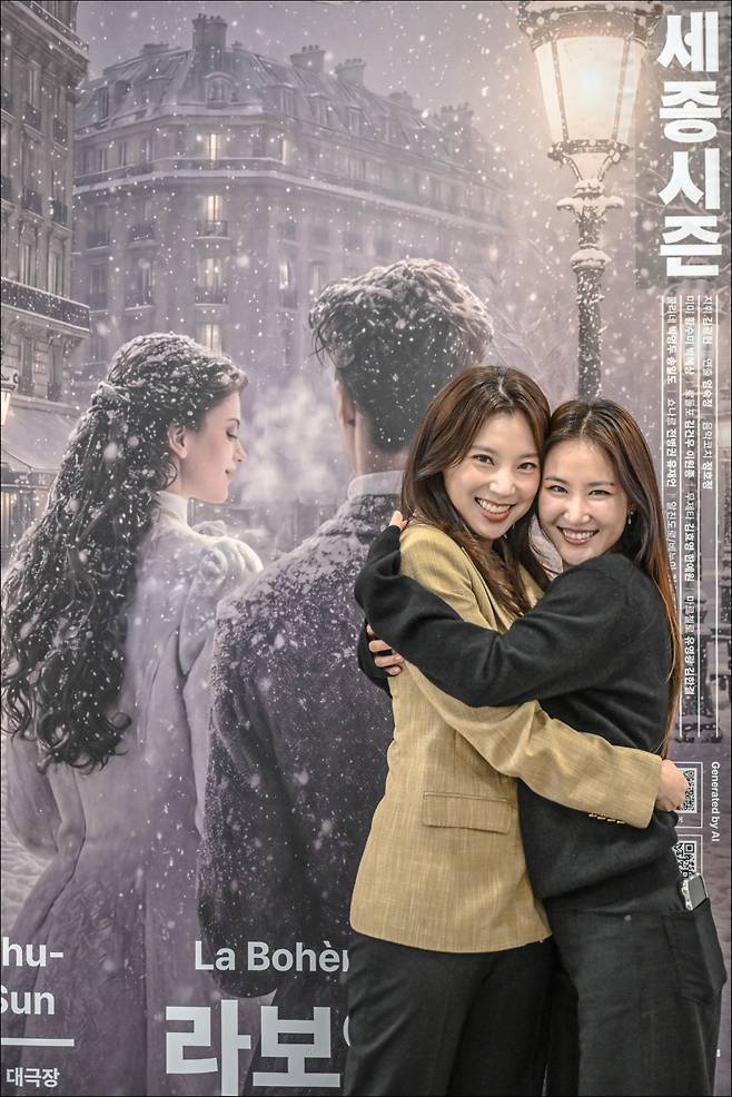 소프라노 황수미(왼쪽)와 박혜상이 오페라 <라보엠> 포스터 앞에서 다정하게 포즈를 취하고 있다. 세종문화회관 제공