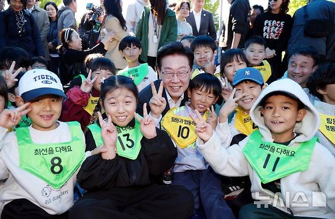 [익산=뉴시스] 김진아 기자 = 이재명 대통령이 22일 전북 익산 왕궁초등학교에서 열린 가을 행복학교 체육한마당에서 학생들과 기념 촬영을 하고 있다. 2026.10.22. bluesoda@newsis.com