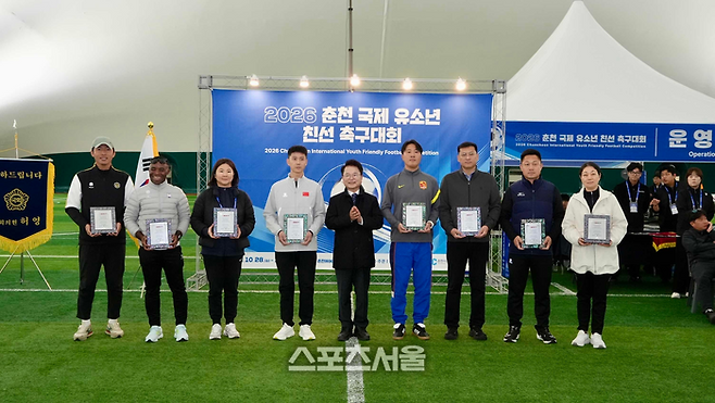 육동한 춘천시장이 ‘2026 춘천 국제 유소년 친선 축구대회’개막식에서 참가팀들에게 참가를 기념하는 기념패를 전달했다.   사진|춘천시청