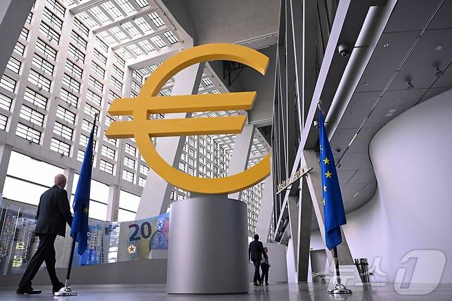 지난 6월 11일(현지시간) 독일 서부 프랑크푸르트에 있는 유럽중앙은행(ECB) 본부에서 한 방문객이 대형 유로화 기호 조형물 앞을 지나가고 있다. ECB는 이란 전쟁에 따른 인플레이션 압력이 커지면서 유로존의 경기 둔화 우려에도 이날 2023년 이후 처음으로 금리를 인상할 것으로 예상됐다. 2026.6.11 ⓒ AFP=뉴스1