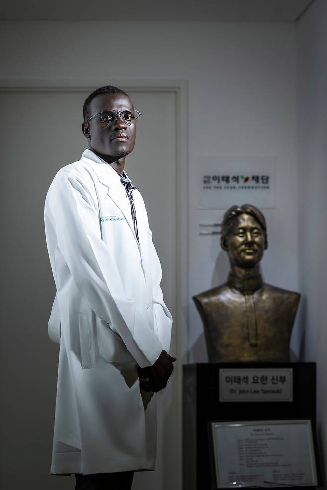 조셉 볼이 서울 영등포구 이태석재단에 있는 이 신부의 동상 앞에 서 있다. 볼은 “신부님은 내게 아버지와 같은 존재”라고 했다. /이건송 영상미디어 기자