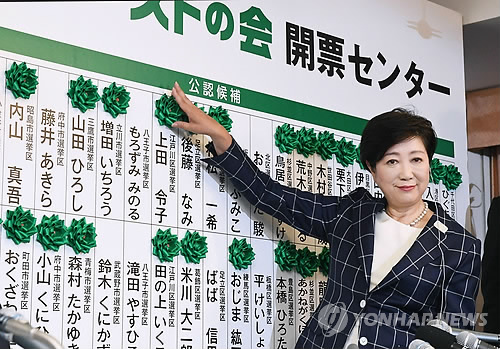 (도쿄 AP=연합뉴스) 고이케 유리코 일본 도쿄 도지사가 2일(현지시간) 실시된 도쿄도 의회 선거에서 당선이 확정된 후보들의 이름에 장미 리본을 달며 미소짓고 있다.       ymarshal@yna.co.kr