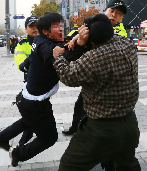 2014년 12월 11일 한 청년단 회원이 광화문 세월호 농성장 철거를 시도하며 시민과 몸싸움을 벌이고 있다. [중앙포토]