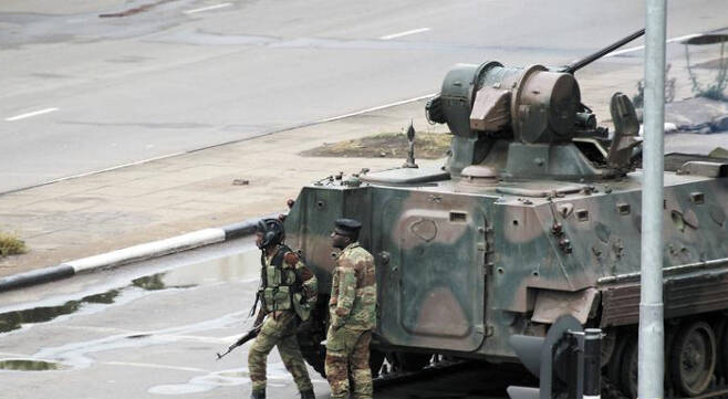 짐바브웨 수도 하라레 거리에 등장한 탱크 - 15일(현지 시각) 군부 쿠데타가 발생한 짐바브웨 수도 하라레 거리에 무장 군인들이 탱크 옆에서 경계를 서고 있다. 이날 새벽 무가베의 저택 인근에서 수십 발의 총성이 들렸고, 하라레 중심가에서 큰 폭발음이 들렸다. /AP 연합뉴스