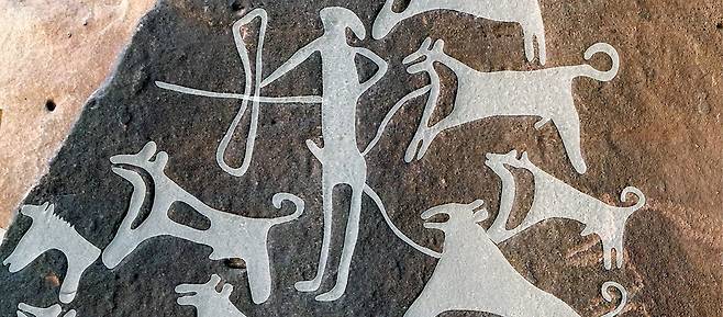 사우디아라비아 슈와이미스 유적지에서 발견된 암각화. 활을 든 사냥꾼과 줄에 묶인 개들이 그려져 있다./독일 막스플랑크 연구소