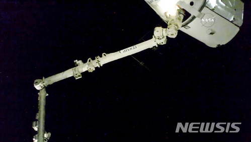 우주정거장의 로봇팔이 17일 도착한 우주화물선 캡슐 드래곤을 끌어당기고 있다. NASA/AP.